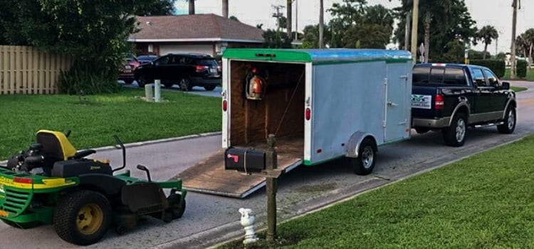 A large lawn mower being unloaded from a trailer.