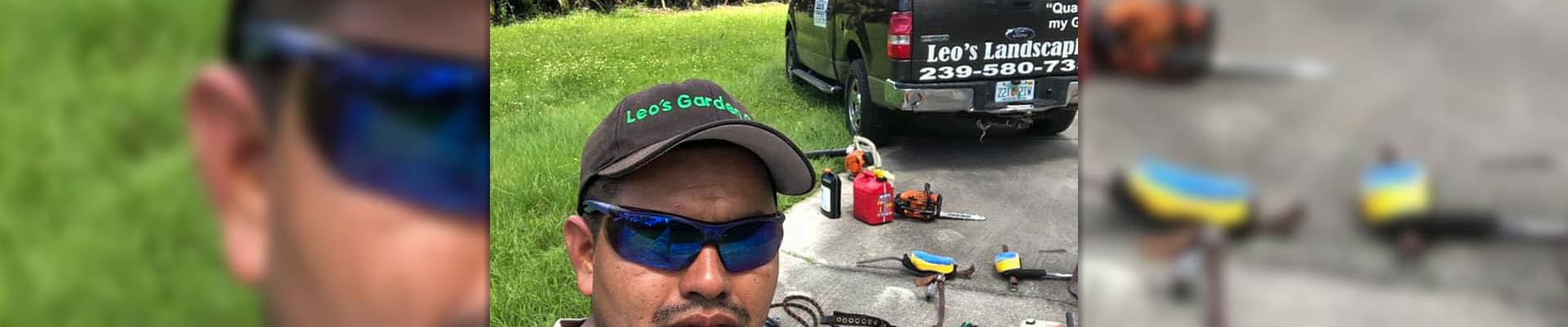 The owner of Leo Garden Care wearing a Leo Garden Care hat, standing in front of a truck bearing the company's logo.