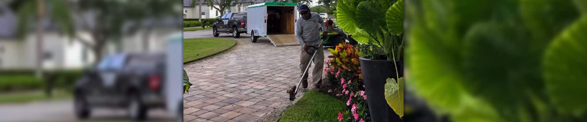 Employee of Leo Garden Care using a stick edger to complete lawn care service.